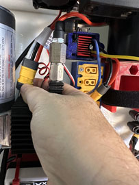 A hand holding a black and red electrical device

AI-generated content may be incorrect.