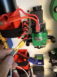 A hand holding a wire to a green and red electrical device

AI-generated content may be incorrect.